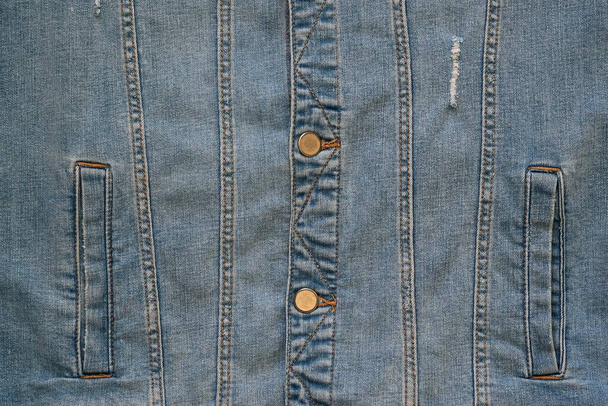 the front part with the lower pockets of a worn blue denim jacket is a closeup - Photo, Image