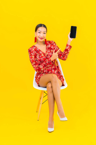 Retrato bonito jovem asiático mulher uso inteligente telefone celular sentar na cadeira - Foto, Imagem