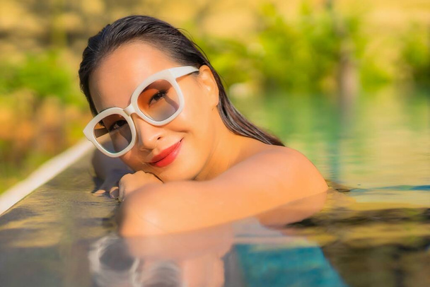 ポートレートの美しい若いアジアの女性はレジャー休暇のためのプールの周りのリラックスを楽しむ - 写真・画像