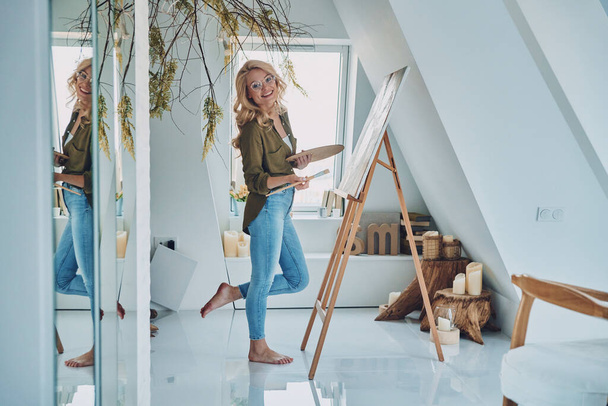 Full length of attractive young woman painting in art studio - Fotó, kép