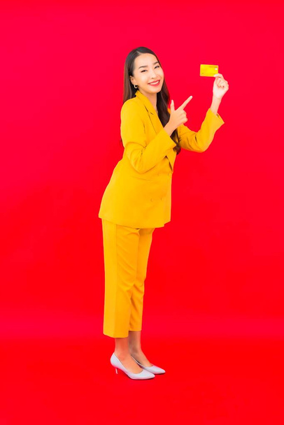 Ritratto bella giovane donna asiatica usa cellulare con carta di credito su sfondo rosso - Foto, immagini