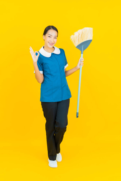 Porträt schöne junge asiatische Frau Dienstmädchen und Haushälterin Lächeln mit Aktion auf gelbem Hintergrund - Foto, Bild