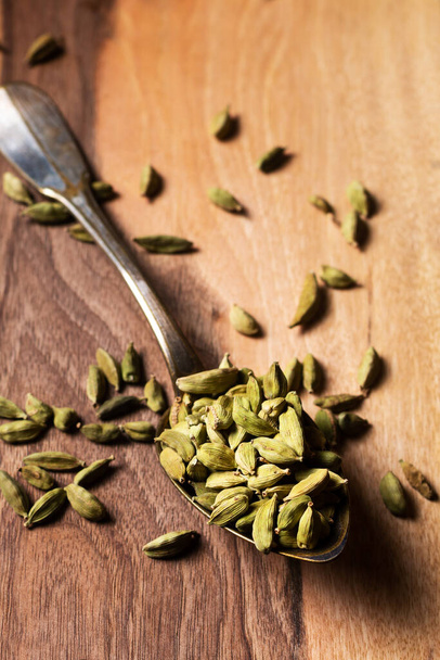 Food concept green Cardamom, cardamon, cardamum pods on vinatge spoon on wooden board with copy space - Foto, Imagem