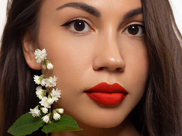 Close-up beauty of female face withevening make-up. Black arrows on the eyes and extremely long eyelashes, on full red lips matte scarlet lip color. Well-groomed skin. Smile and white teeth - Photo, Image