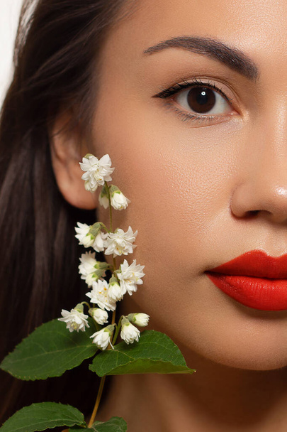 Half Beauty closeup of women full red lips with shiny skin and long hair. Facial skin care in a spa salon or cosmetology and a fashionable natural lip gloss or lipstick. Evening makeup with big flower - Foto, Bild