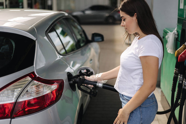 Woman is refueling at gas station. Female hand filling benzine gasoline fuel in car using a fuel nozzle. Petrol prices concept - Zdjęcie, obraz