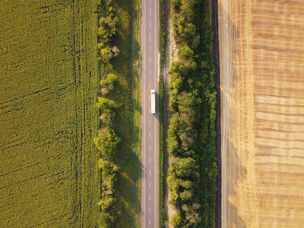 Πάνω προς τα κάτω άποψη σε ασφαλτοστρωμένο δρόμο με φορτηγό μεταξύ δύο γεωργικών αγρών. - Φωτογραφία, εικόνα