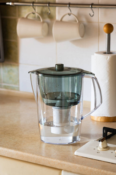 Dzbanek z filtrem wody na kuchennym stole. Koncepcja czystej wody. Woda filtracyjna - Zdjęcie, obraz