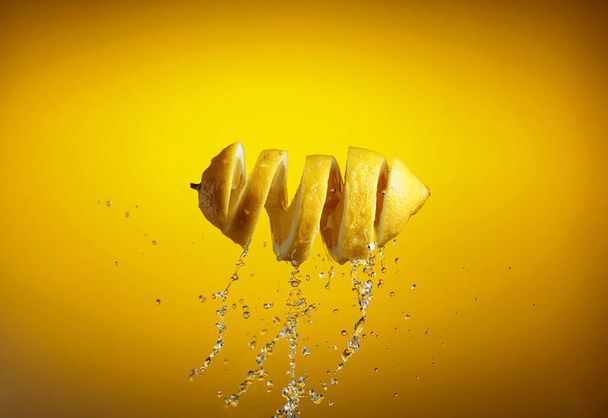 Fresh lemon and splashes on a yellow background. - Photo, Image