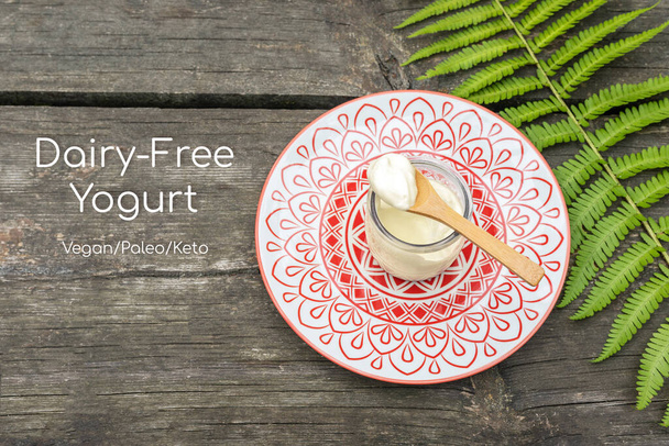 Dairy-free yogurt. Product for vegan, paleo, keto diet. Eco friendly, food, composition with organic, vegan, homemade yogurt and fern leave on a wooden background with inscription dairy free yogurt - 写真・画像