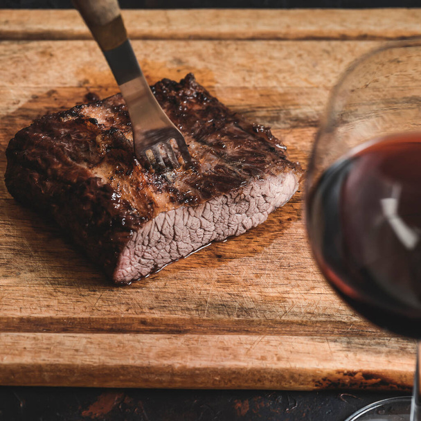 Pečená hovězí žebírka se sklenkou červeného vína na stole, tradiční argentinská kuchyně, gril Asado, Patagonia, Argentina. - Fotografie, Obrázek