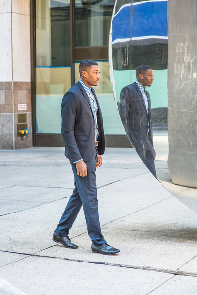 Ένας νεαρός μαύρος επιχειρηματίας περπατάει, περνάει από έναν καθρέφτη, και σκέφτεται - Φωτογραφία, εικόνα