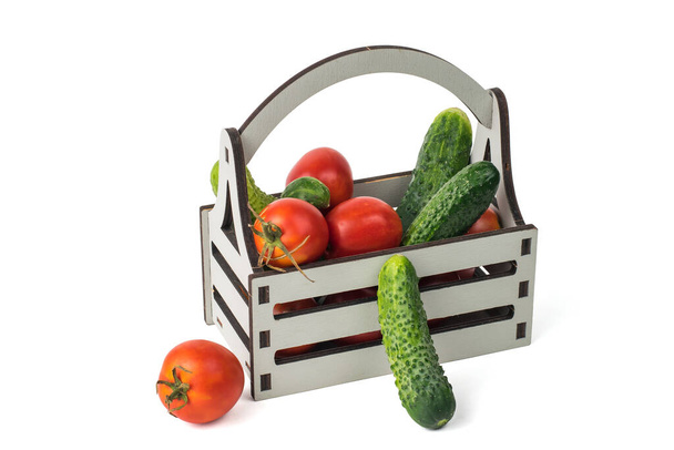 Een doos met verse komkommers en tomaten geïsoleerd op een witte achtergrond. Een vers gewas van groenten. - Foto, afbeelding