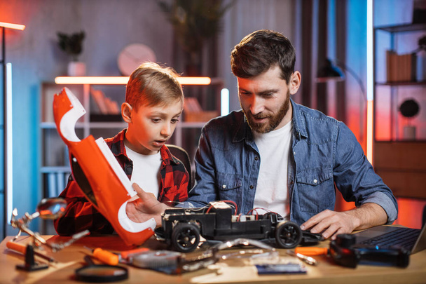 Father helping his son to fix favorite toy car at home - Foto, afbeelding
