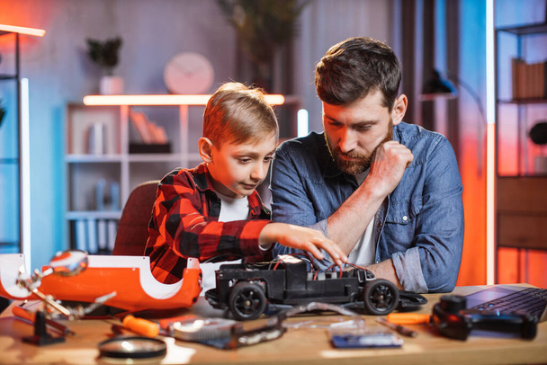 Father teaching his son to repair red toy car - Zdjęcie, obraz