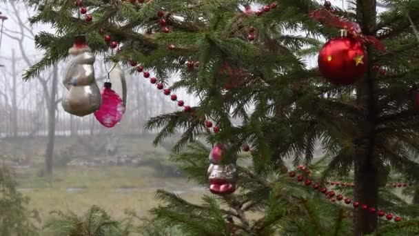 Bugigangas vintage e bolas de Natal vermelhas balançam nos galhos da árvore de Natal ao ar livre - Filmagem, Vídeo