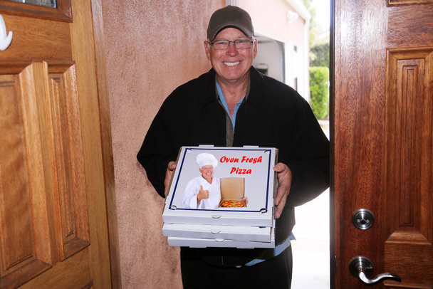 Entrega de pizza. El repartidor de pizza. Un hombre guapo y amigable de la entrega de la pizza trae la pizza fresca caliente a su hogar u oficina para la cena o el almuerzo. Un repartidor de pizza sosteniendo cajas de pizza. Smiling Pizza Delivery Man At Doorstep. Pizza Pizza. Almuerzo de pizza - Foto, imagen