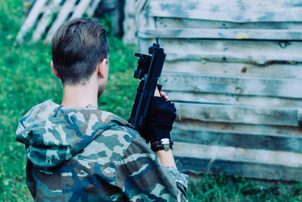 A young soldier in a military camouflage uniform with a marker for playing paintball - Fotoğraf, Görsel
