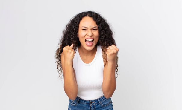 pretty hispanic woman feeling shocked, excited and happy, laughing and celebrating success, saying wow! - Photo, image