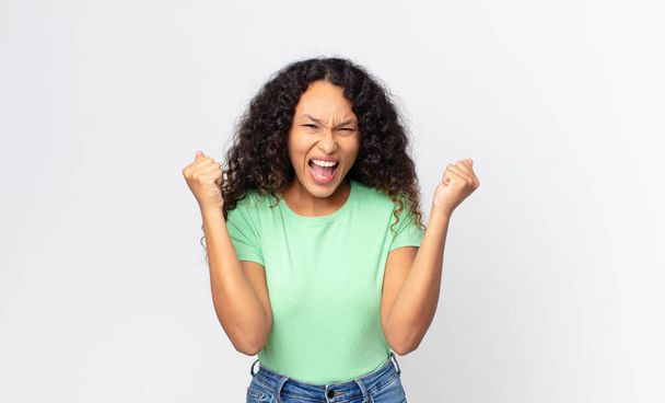 pretty hispanic woman looking extremely happy and surprised, celebrating success, shouting and jumping - Foto, Imagem