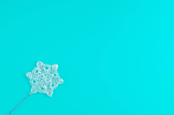 Glass pendant snowflake on a turquoise background. Place for your text. - Photo, Image
