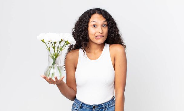 hispanic pretty woman looking puzzled and confused and holding a flowers jar - Foto, immagini