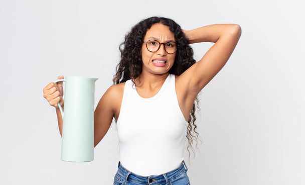 hispánská hezká žena pocit stresu, úzkosti nebo strach, s rukama na hlavě a drží kávu termosku - Fotografie, Obrázek