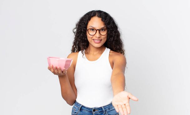 hispanic pretty woman smiling happily with friendly and  offering and showing a concept and holding an empty pot - Фото, изображение