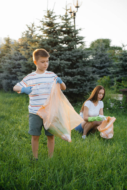A group of girls with children at sunset are engaged in garbage collection in the park. Environmental care, recycling. - Photo, image