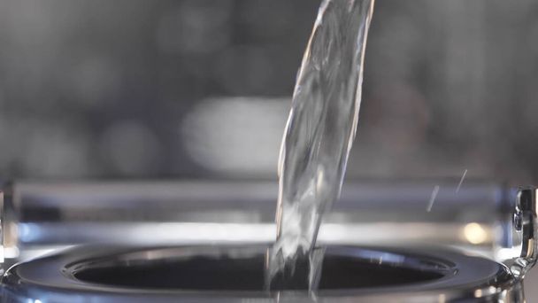 Close-up de água sendo derramada em chaleira de metal. Acção. A corrente de água limpa é vertida na chaleira. A água é derramada em bule de metal para chá - Foto, Imagem