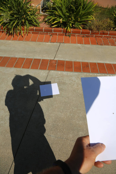 Sonnenfinsternis. Sonnenfinsternis 2017. Ein Mann benutzt ein Nadelloch in einem Blatt Papier, um die Sonnenfinsternis am 21. September 2017 zu fotografieren. Schatten mit Sonnenfinsternis. Eine Sonnenfinsternis tritt ein, wenn der Mond vollständig auf der Bahn der Sonne steht. Sonnenfinsternis. - Foto, Bild