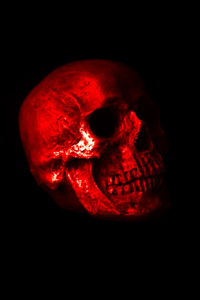 Human Skull. Halloween. Scary. Spooky. Halloween Human Skull. A Spooky Monstrous Human Skull Isolated on Black. Red light on a human skull in the night. Covid-19 Halloween Human Skull. Coronavirus Skull. Grim reaper reaching towards you the viewer. - Photo, Image