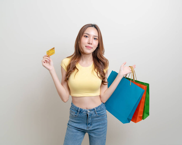 portrait beautiful Asian woman holding shopping bag and credit card on white background - Fotografie, Obrázek