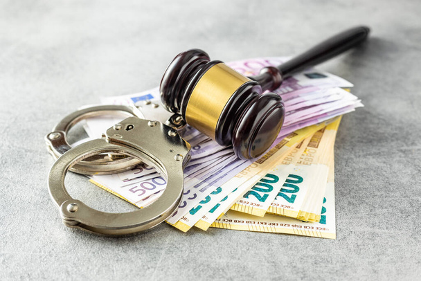 Euro banknotes, judge gavel and handcuffs on rusty table. - Photo, image