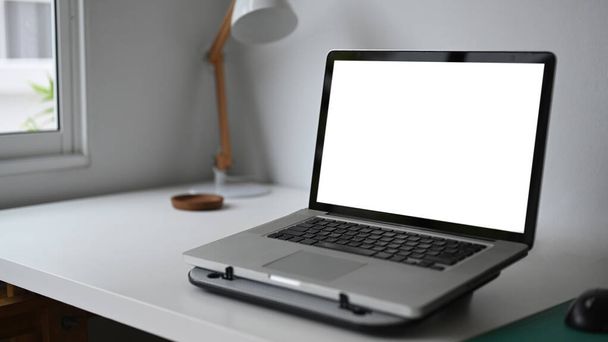 Απλός χώρος εργασίας με laptop σε λευκό ξύλινο τραπέζι.Κενή οθόνη για γραφικά μοντάζ οθόνη. - Φωτογραφία, εικόνα