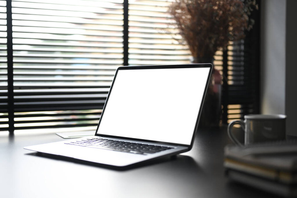 Een open blanco scherm computer laptop op zwarte tafel in hedendaagse werkruimte. - Foto, afbeelding