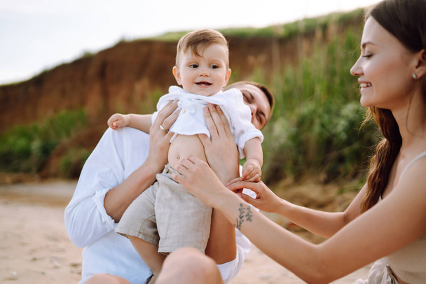 Happy young family with little baby boy spending time together on the beach. Family, childhood, ecology and people. - Zdjęcie, obraz