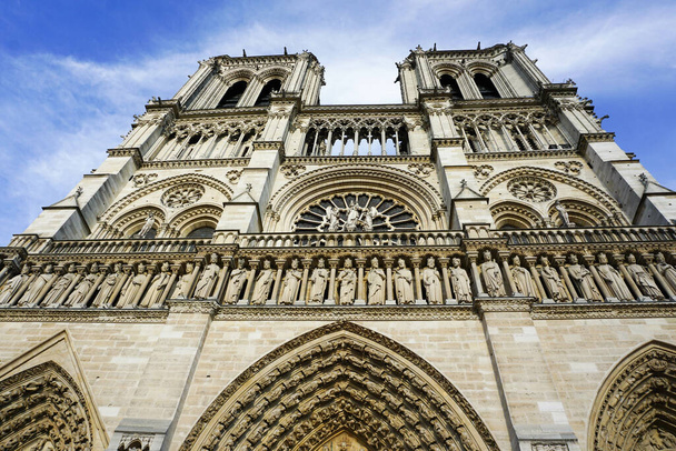 A low angle shot of Cathedrale Notre-Dame de Paris under a blue cloudy sky in France - Foto, Imagem