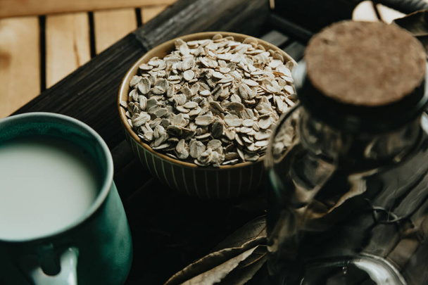 Ein Frühstück aus einer Tasse Hafermilch mit Hafersamen auf einem Holztisch - Foto, Bild