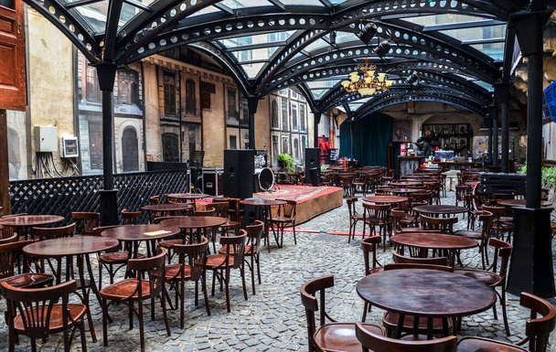 Original design of a covered terrace of a street cafe with empty wooden tables and chairs in center of Lviv, Ukraine - Fotó, kép