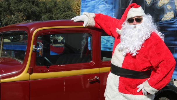 Άγιε Βασίλη. Αυτοκίνητο. Χριστούγεννα. Χριστουγεννιάτικο δώρο. Santa Claus παραδίδει ένα κόκκινο Hot Rod αγωνιστικό αυτοκίνητο για τα Χριστούγεννα. Ο Άγιος Βασίλης ετοιμάζεται για τα Χριστούγεννα. Ο Άγιος Βασίλης σε διακοπές. Παραδίδω χριστουγεννιάτικα δώρα. Ο Άγιος Βασίλης οδηγεί ένα Hot Rod Car. Χο Χο. - Φωτογραφία, εικόνα