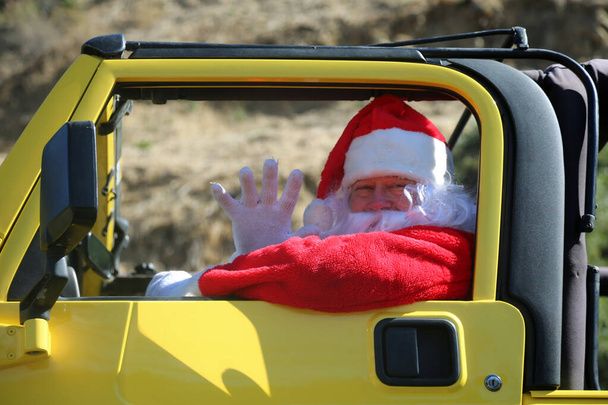 Père Noël. Voiture. Noël. Cadeau de Noël. Le Père Noël pose pour son portrait avec sa voiture. Le Père Noël se prépare pour Noël. Père Noël en vacances. Père Noël en voiture verte offrant des cadeaux de Noël. Père Noël conduisant une voiture jaune.  - Photo, image