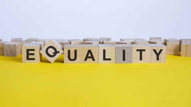 EQUALITY word is made of wooden building blocks lying on the yellow table, concept - Photo, Image