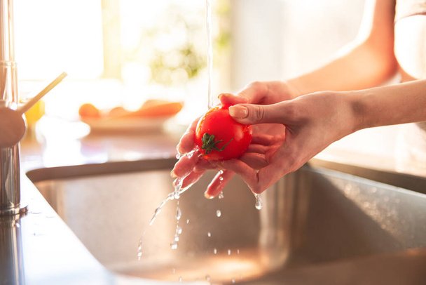 Nainen puhdistaa tomaatit keittiössä kotonaan valaistu aurinko - Valokuva, kuva