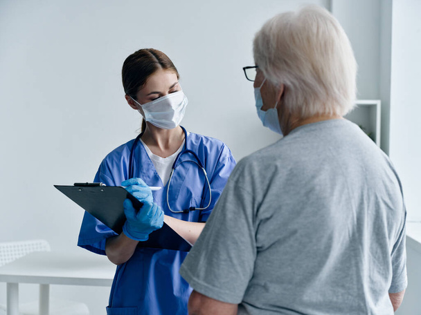 female nurse in medical mask and scraping talking to elderly patient covid passport - Foto, Imagem