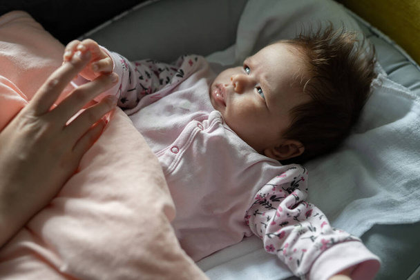 小さなcaucasian赤ちゃん男の子または女の子2ヶ月嘘でベッド開催彼女のお母さん手成長子供時代と育児の概念 - 写真・画像