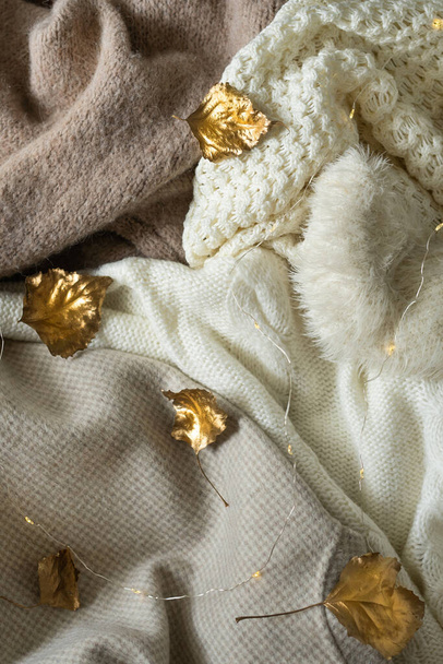 Pile of knitted clothes with autumn gold leaves, warm background, knitwear, space for text, Autumn winter concept. - Foto, immagini