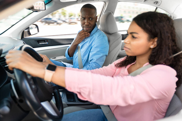 przerażony instruktor patrząc na poważnie skupiony czarny kobieta kierowca - Zdjęcie, obraz