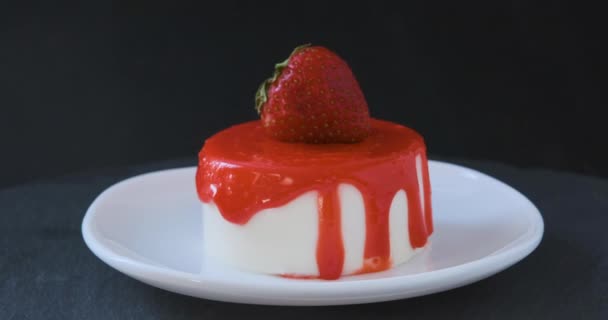 Eet smakelijke fruitcake versierd met verse aardbeien. Roterende zomer dessert op schotel op zwarte achtergrond.  - Video