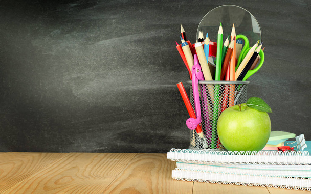 教室のテーブルの上に鉛筆ホルダーと学校のノートと緑のリンゴ - 写真・画像